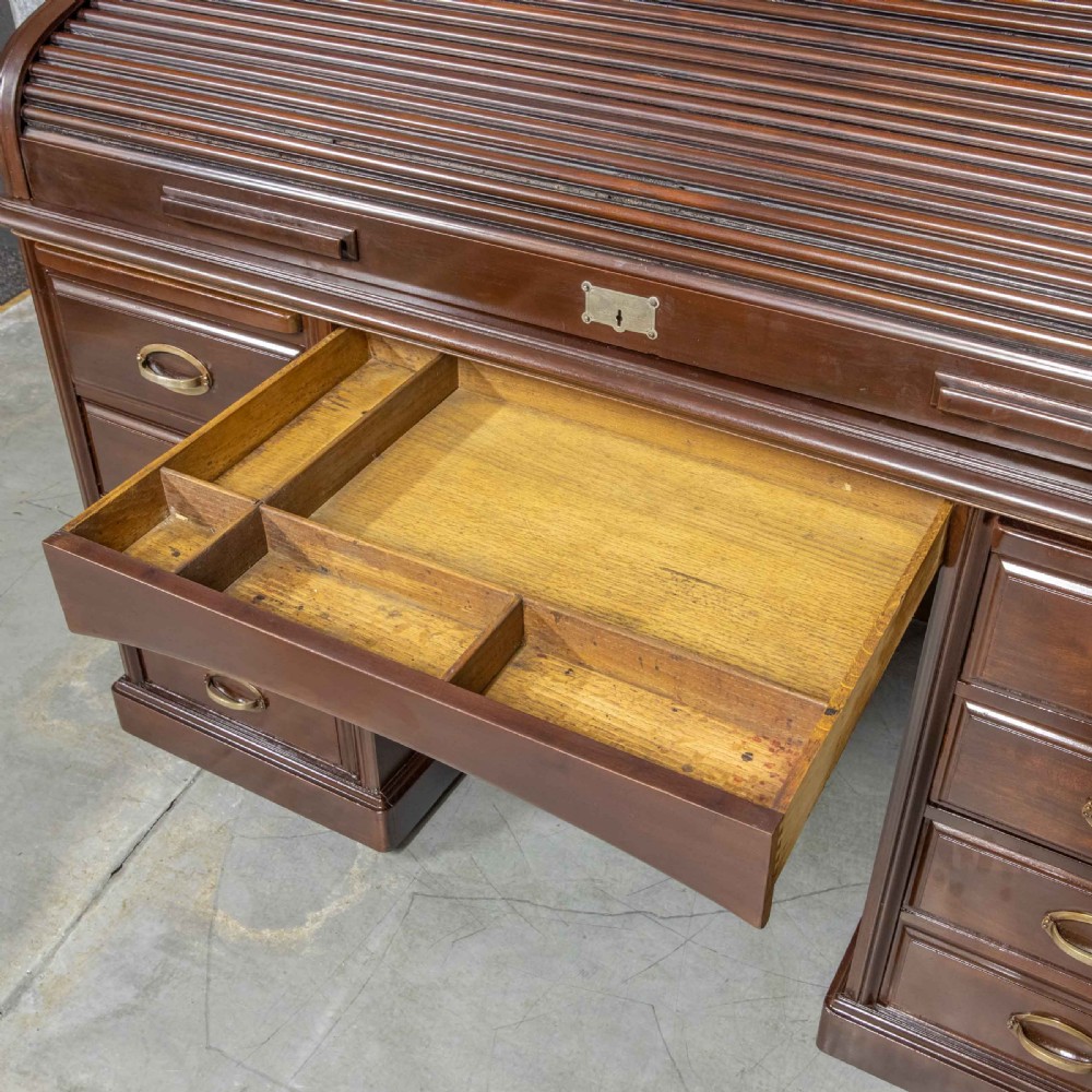 An Edwardian walnut double-pedestal roll top desk featuring a slatted tambour cover, inset green leather writing surface, multiple small interior drawers, and twin pedestal drawers with brass handles. View XXII