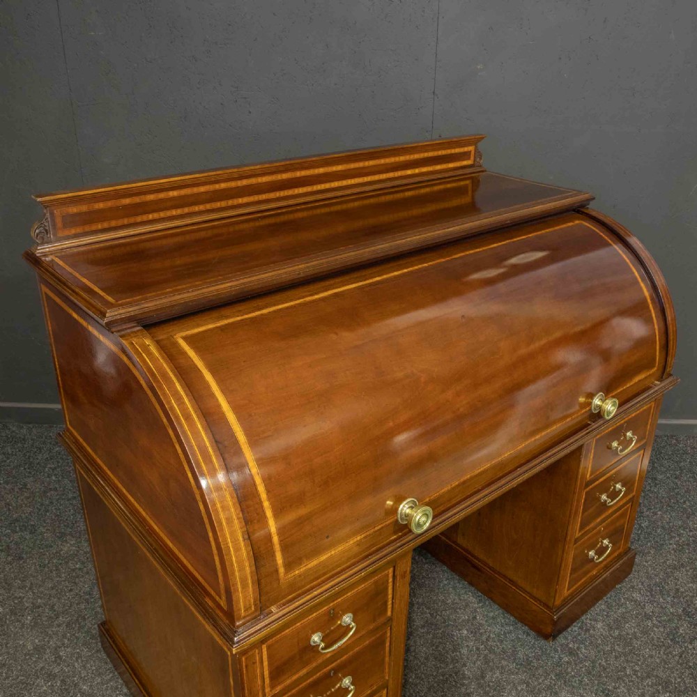 An antique mahogany cylinder desk featuring inlaid satinwood borders, a pull-out leather writing slope, fitted pigeonholes, and twin drawer pedestals. View VI