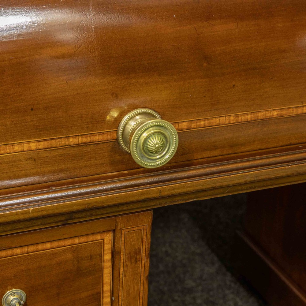 An antique mahogany cylinder desk featuring inlaid satinwood borders, a pull-out leather writing slope, fitted pigeonholes, and twin drawer pedestals. View VII