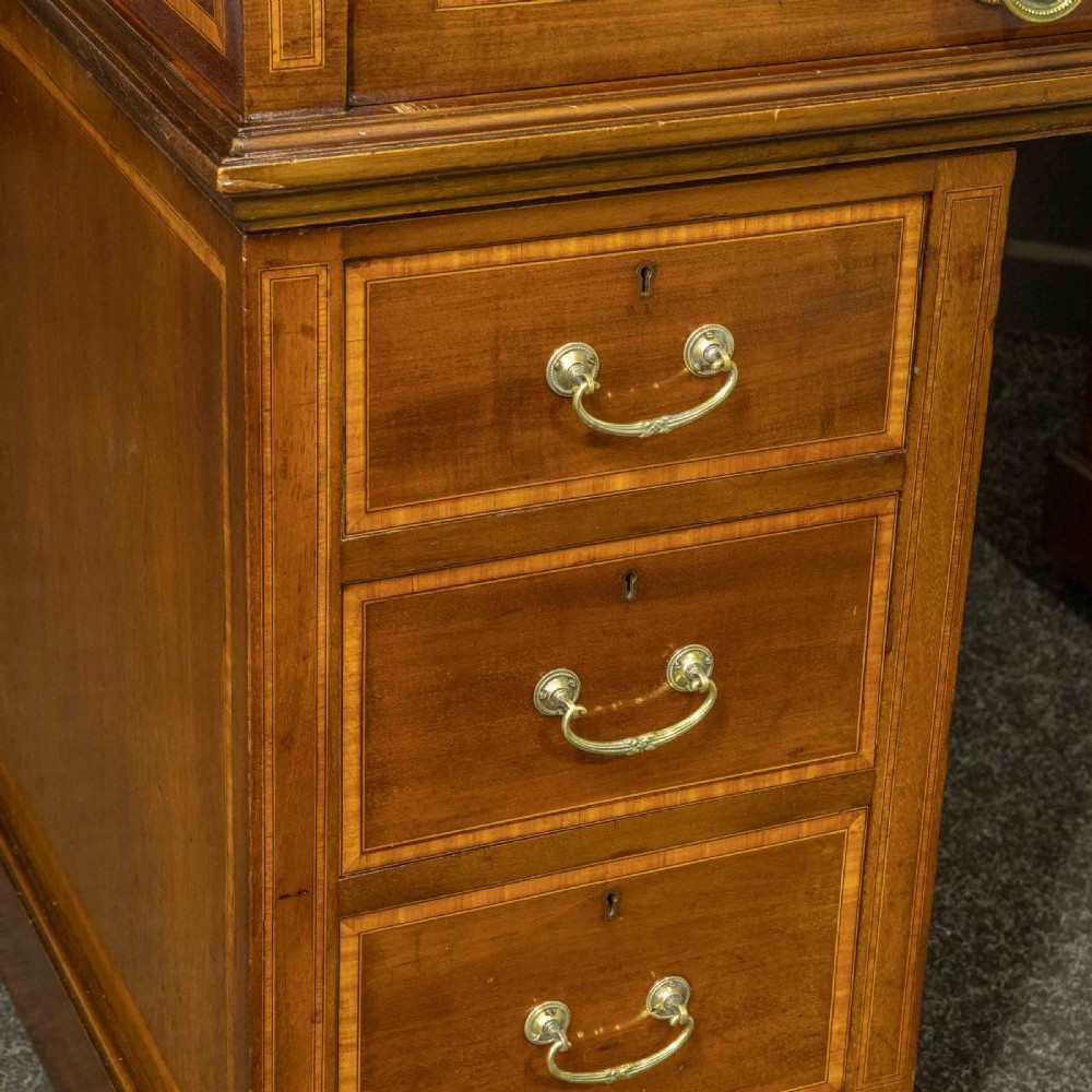 An antique mahogany cylinder desk featuring inlaid satinwood borders, a pull-out leather writing slope, fitted pigeonholes, and twin drawer pedestals. View IX