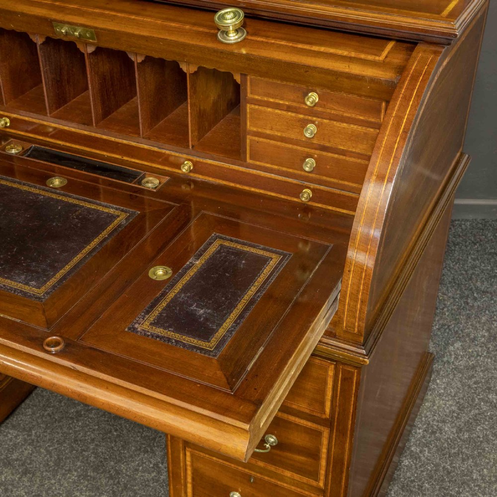 An antique mahogany cylinder desk featuring inlaid satinwood borders, a pull-out leather writing slope, fitted pigeonholes, and twin drawer pedestals. View XIII