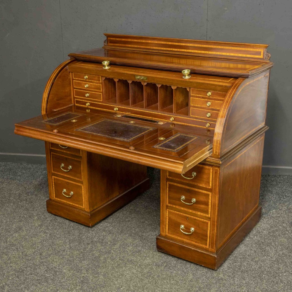 An antique mahogany cylinder desk featuring inlaid satinwood borders, a pull-out leather writing slope, fitted pigeonholes, and twin drawer pedestals. View XIV