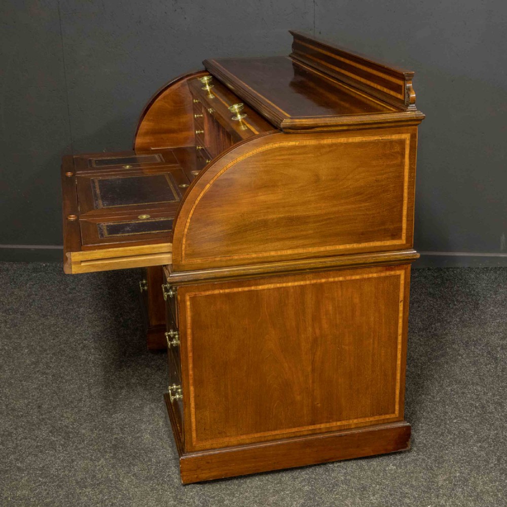 An antique mahogany cylinder desk featuring inlaid satinwood borders, a pull-out leather writing slope, fitted pigeonholes, and twin drawer pedestals. View XV