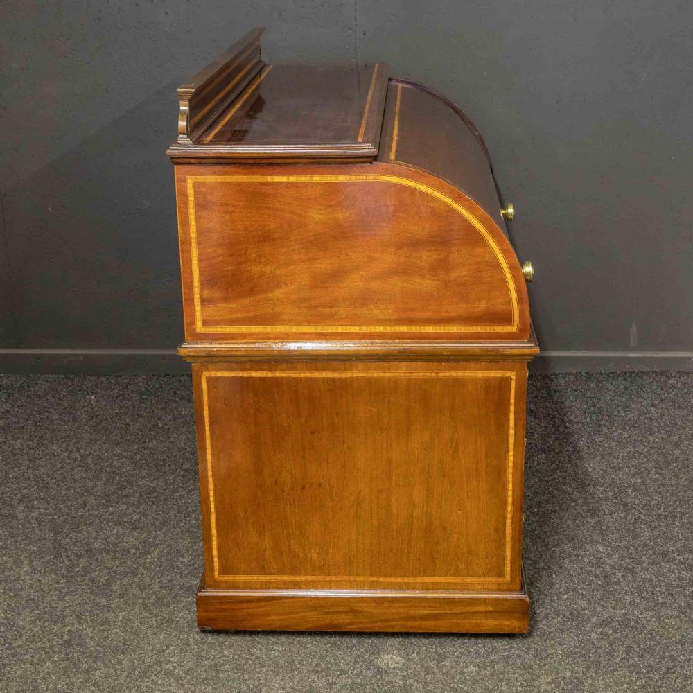 An antique mahogany cylinder desk featuring inlaid satinwood borders, a pull-out leather writing slope, fitted pigeonholes, and twin drawer pedestals. View XVII
