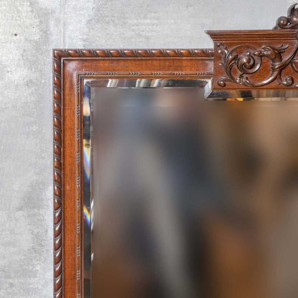 A rectangular Victorian Chippendale style mahogany wall mirror featuring a carved urn cresting, decorative scrollwork, and bevelled glass. View V