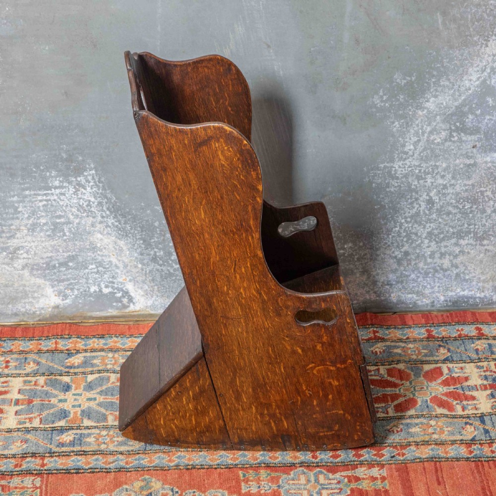 A small antique dark oak childs lambing chair featuring shaped wing sides, an enclosed back, cut-out carrying handles, and a solid box seat base. View IV