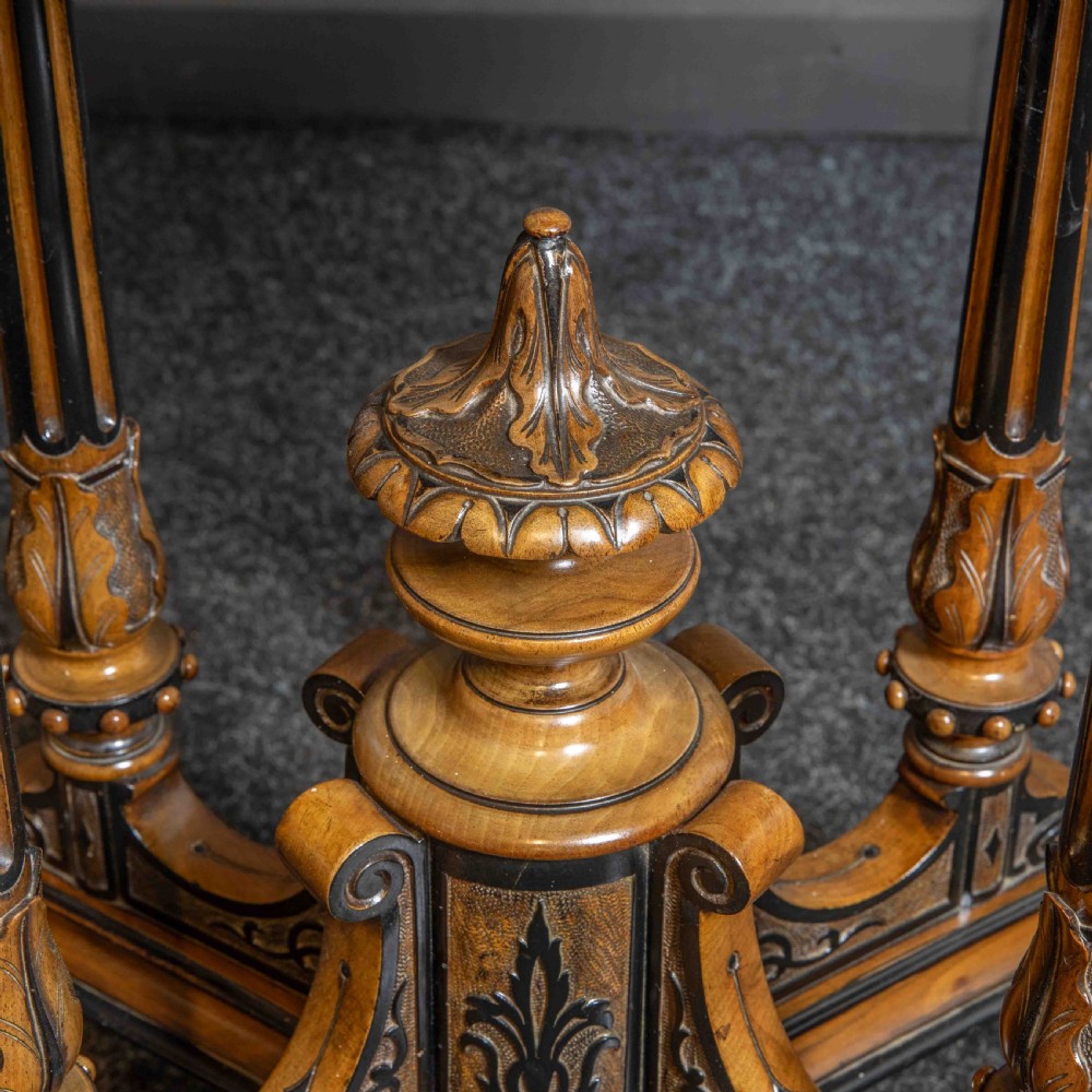 A Victorian Aesthetic Movement card table featuring burr walnut veneer, ebonised borders, turned support columns, and a central carved finial. View VI