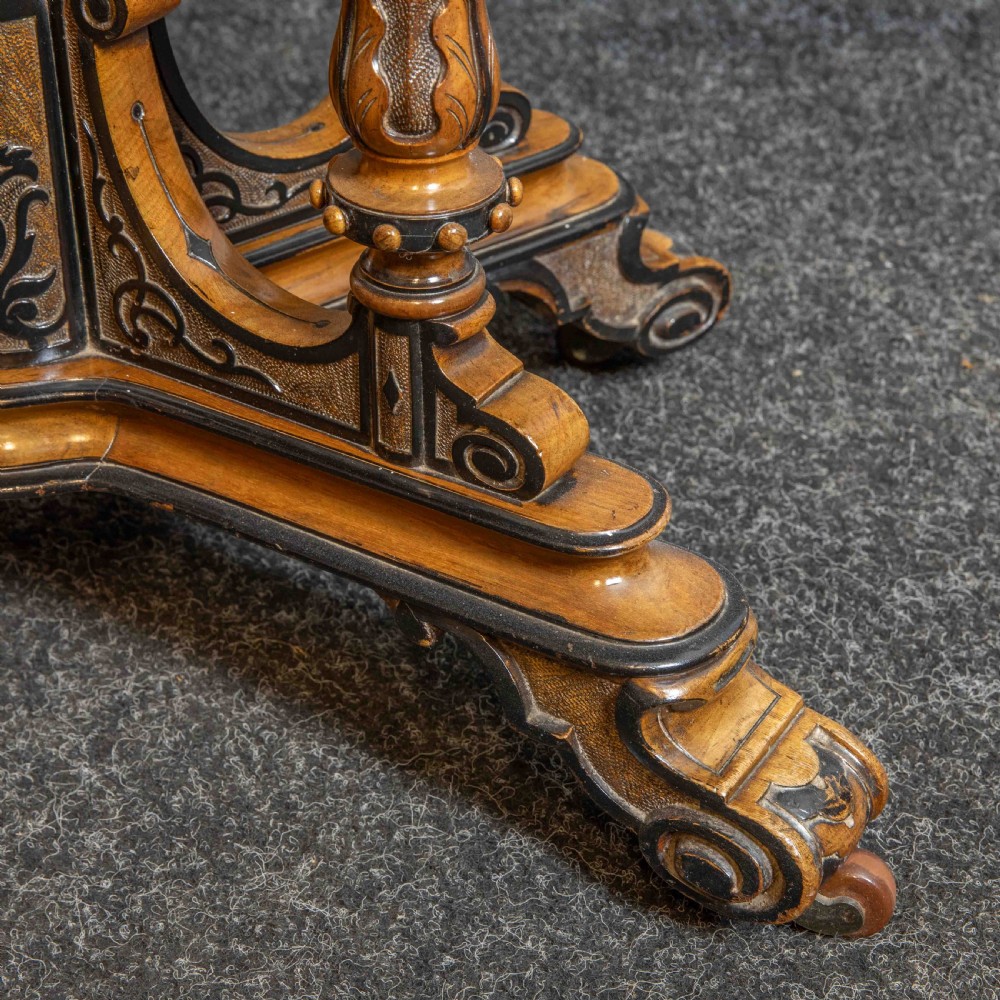 A Victorian Aesthetic Movement card table featuring burr walnut veneer, ebonised borders, turned support columns, and a central carved finial. View VII