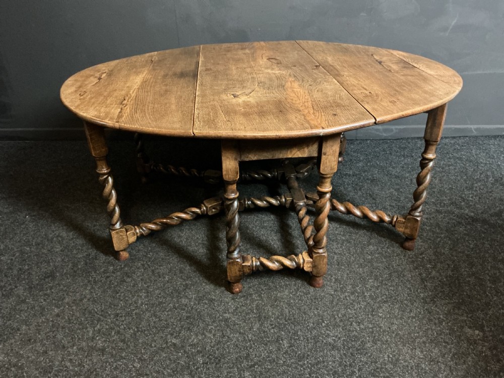 A large round antique oak gateleg dining table featuring drop-leaf flaps and decorative barley twist turned legs. View II