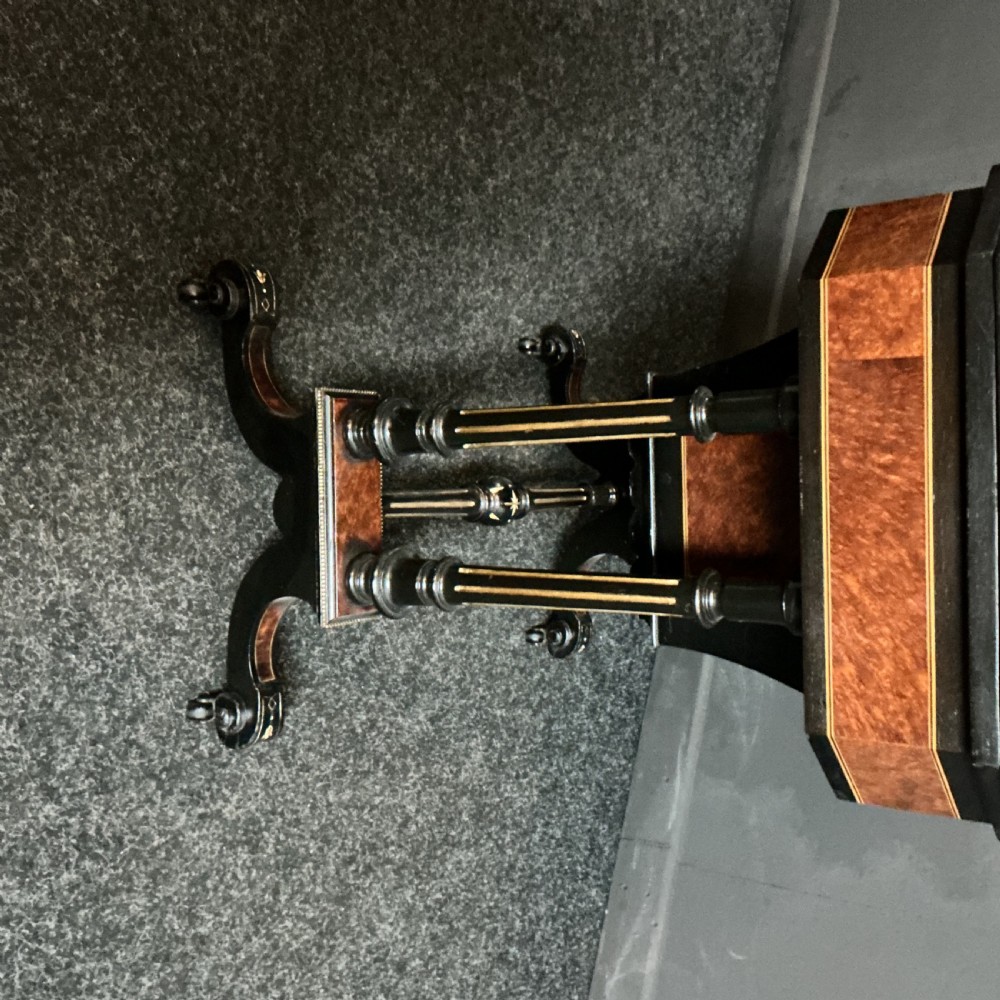 An ebonised Victorian games and sewing table featuring a fold-out top inlaid with chess and backgammon boards supported on turned twin columns. View IV