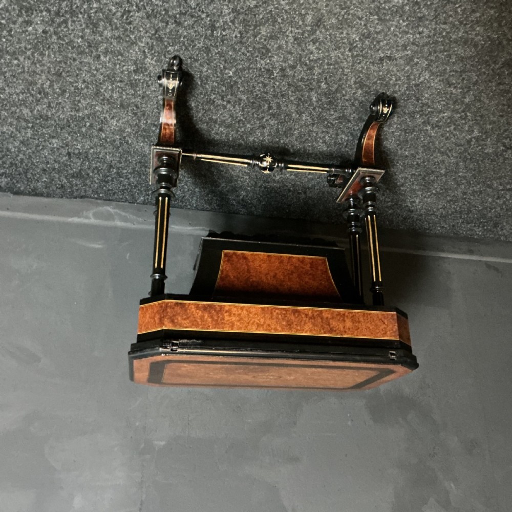 An ebonised Victorian games and sewing table featuring a fold-out top inlaid with chess and backgammon boards supported on turned twin columns. View V