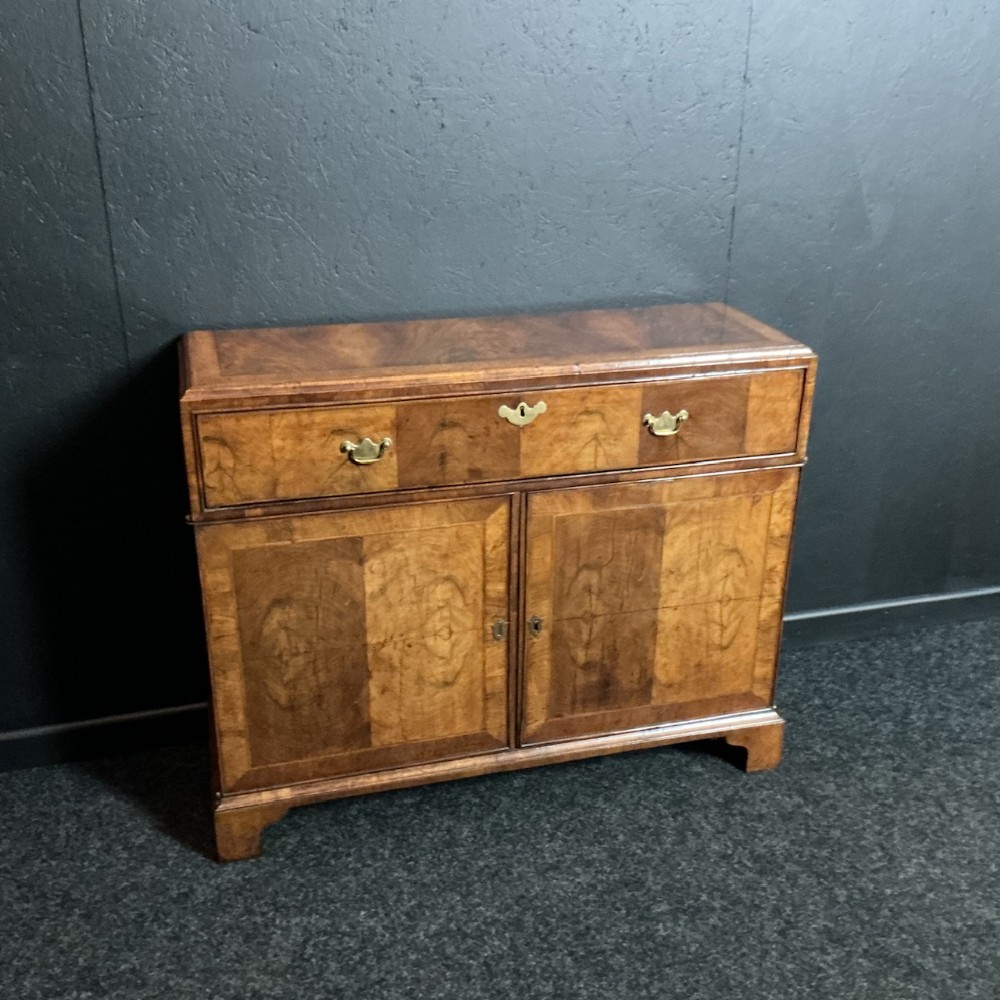 A Queen Anne style walnut storage cupboard featuring a top drawer over a two-door cabinet on bracket feet.