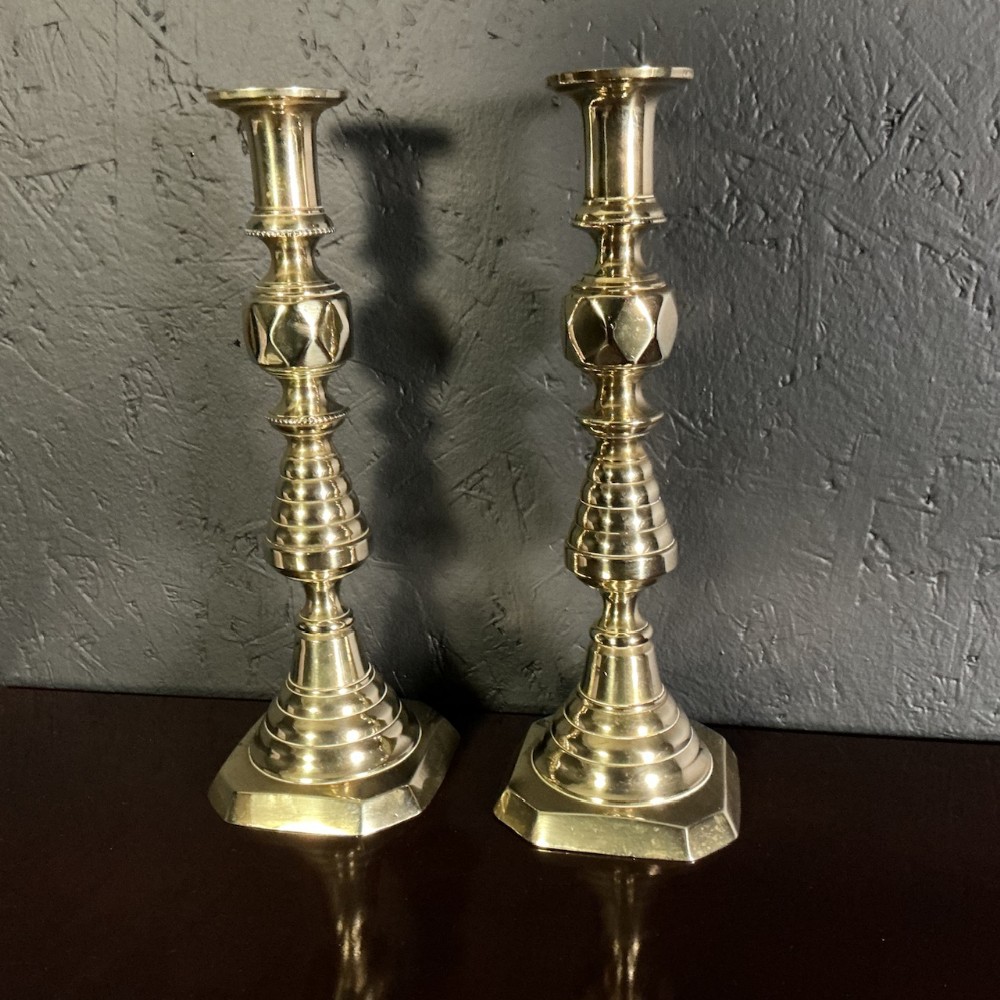 A pair of turned Victorian brass candlesticks with faceted diamond knops and octagonal bases.