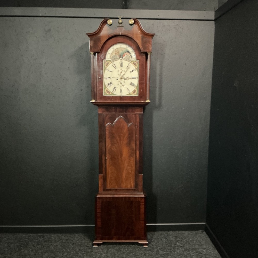 A Georgian mahogany longcase clock featuring a swan-neck pediment, brass details, and a painted dial with a moon phase indicator.