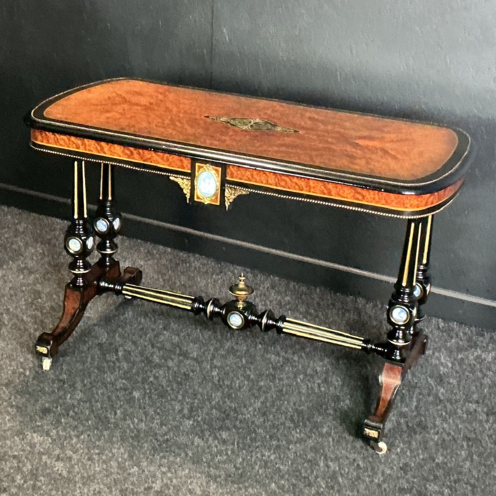 Victorian amboyna and ebonised centre table stamped by Edwards and Roberts, featuring brass inlay, porcelain cabochons, turned legs, and a stretcher.