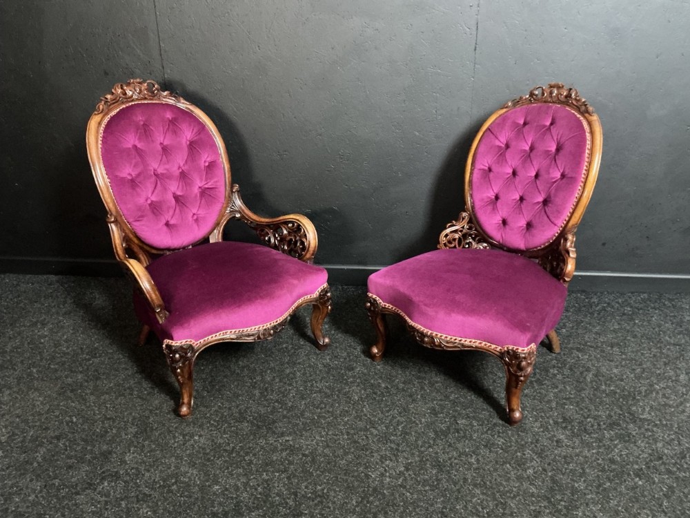 A pair of Victorian carved walnut parlour chairs upholstered in deep buttoned purple velvet with cabriole legs.
