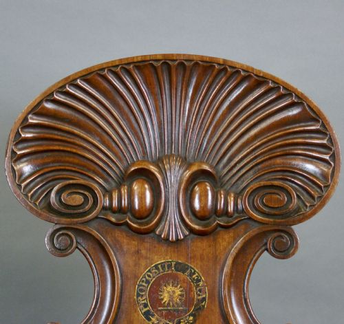fig 1. A pair of carved mahogany hall chairs featuring scalloped shell backs with painted crests and reeded front legs.