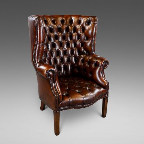 A DEEP BUTTONED CHESTNUT BROWN BARREL BACK WING CHAIR