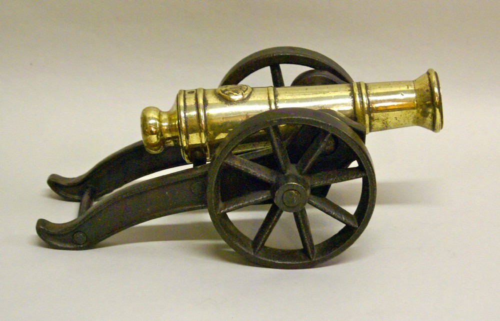 A VICTORIAN BRASS ORNAMENTAL CANNON ON CAST IRON CARRIAGE.