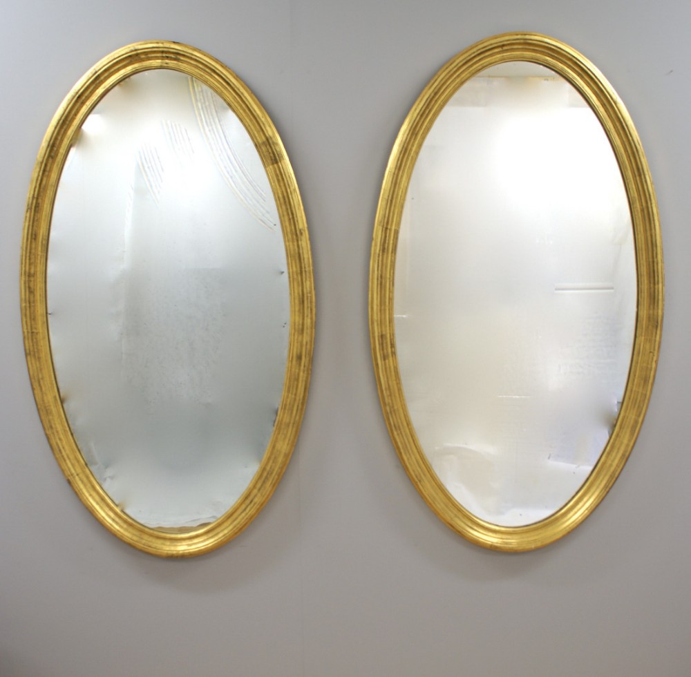 A very large pair of late 19th century oval gilt frame mirrors.