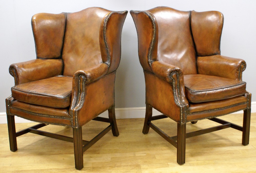 A pair of Georgian style mahogany and leather wing chairs
