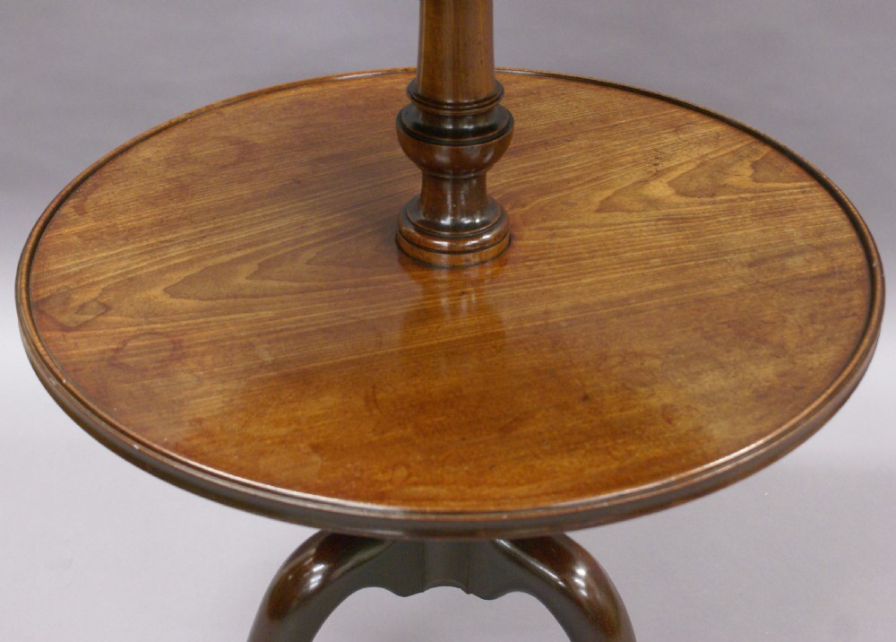 A George III mahogany dumb waiter featuring three graduated circular tiers supported by turned columns on a tripod base with pad feet. View VII