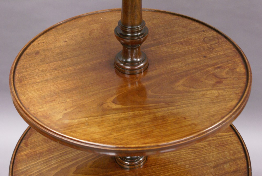 A George III mahogany dumb waiter featuring three graduated circular tiers supported by turned columns on a tripod base with pad feet. View VIII