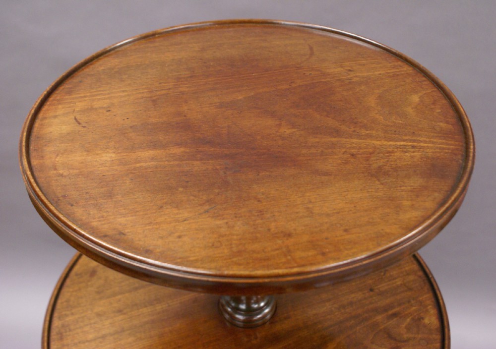 A George III mahogany dumb waiter featuring three graduated circular tiers supported by turned columns on a tripod base with pad feet. View IX