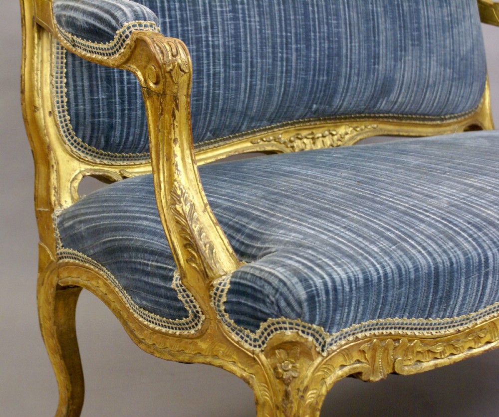 A 19th-century French Rococo-style giltwood sofa featuring a carved gold-leaf frame, cabriole legs, and blue striped fabric upholstery. View III