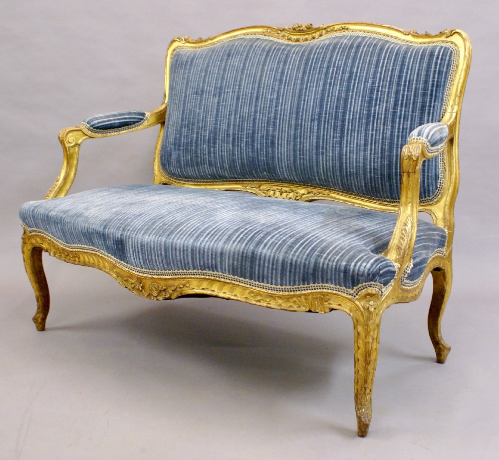 A 19th-century French Rococo-style giltwood sofa featuring a carved gold-leaf frame, cabriole legs, and blue striped fabric upholstery. View V