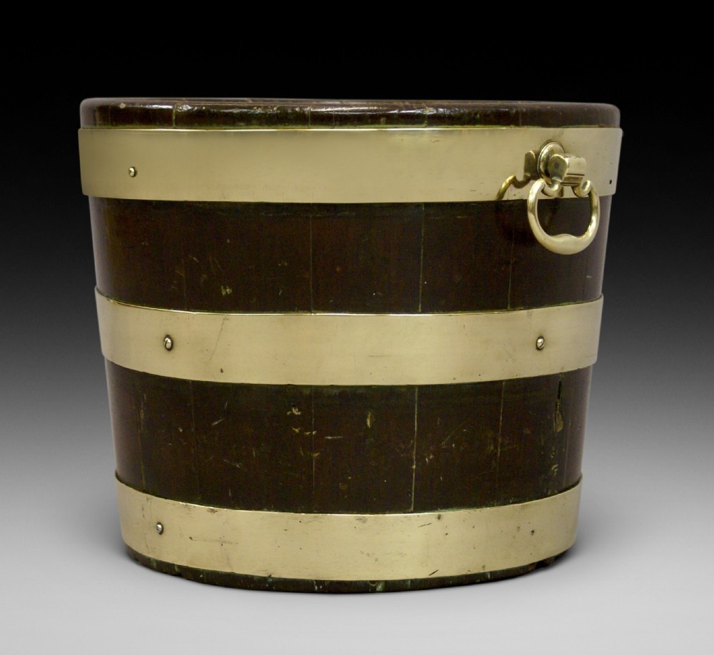 A cylindrical George III mahogany bucket with three horizontal brass bands and brass drop-ring side handles.