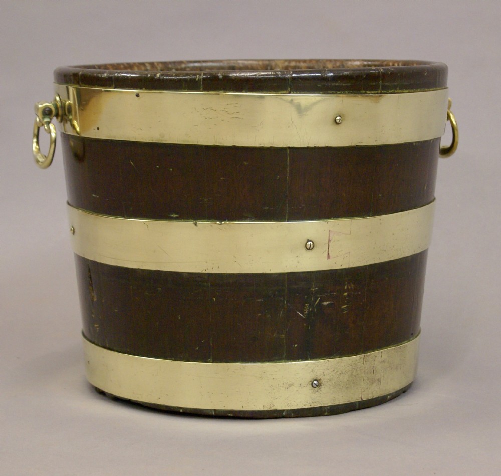 A cylindrical George III mahogany bucket with three horizontal brass bands and brass drop-ring side handles. View III
