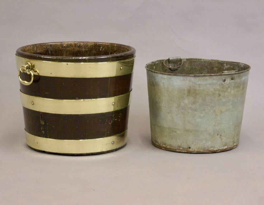 A cylindrical George III mahogany bucket with three horizontal brass bands and brass drop-ring side handles. View V