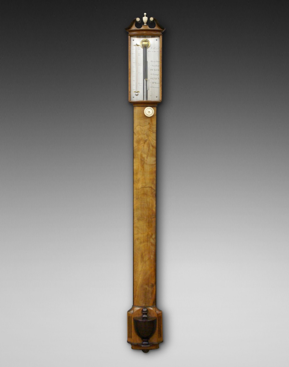A Georgian George III mahogany bow-fronted stick barometer featuring a broken-arch pediment with finial, silvered register plate, and urn-shaped cistern cover.
