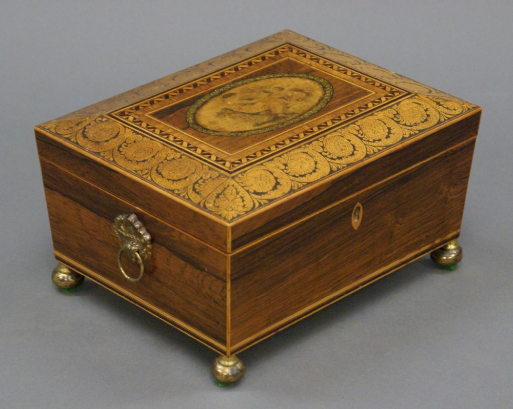 A rectangular dark rosewood Regency sewing box featuring brass ball feet, lion-mask side ring handles, and floral marquetry inlay across the lid. View III