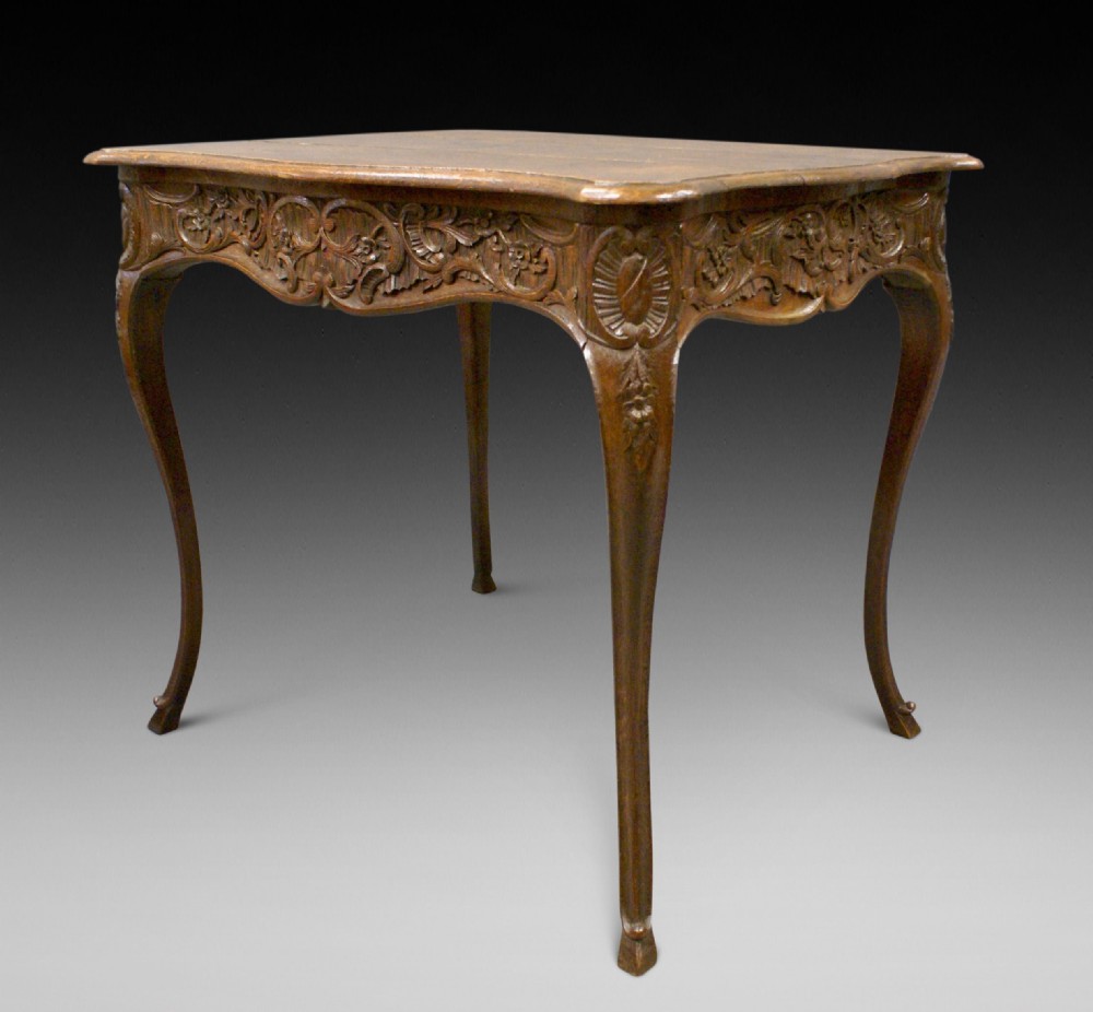 An 18th-century carved oak centre table featuring cabriole legs and detailed floral frieze carving.
