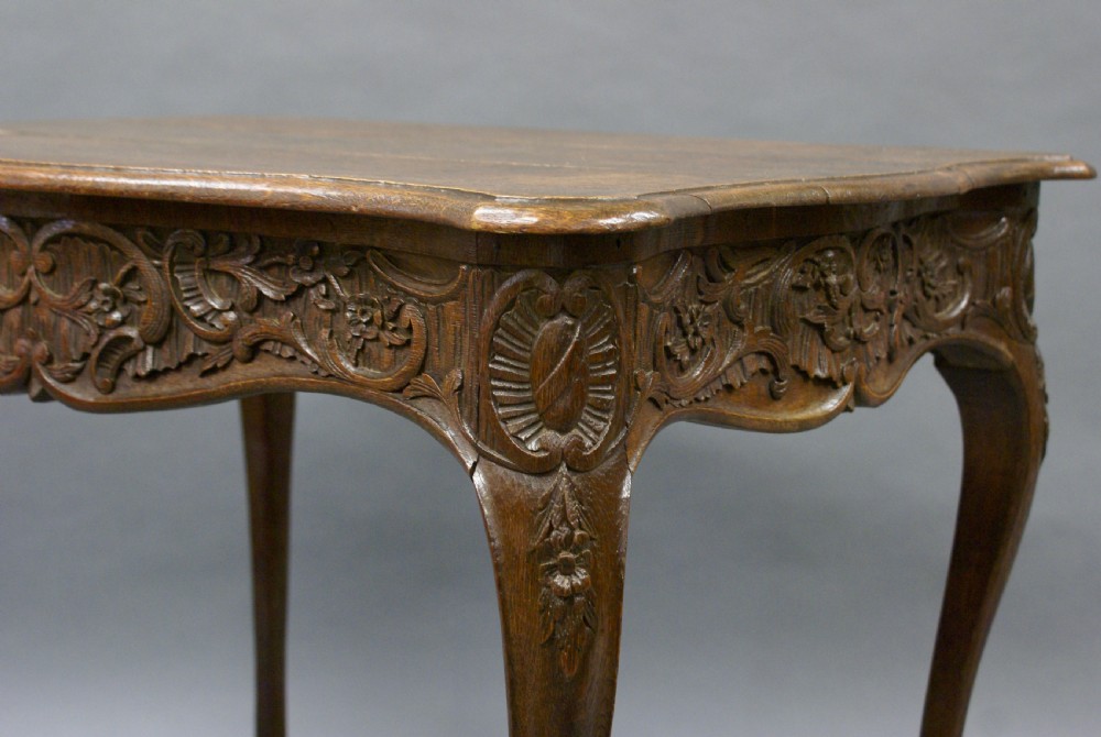 An 18th-century carved oak centre table featuring cabriole legs and detailed floral frieze carving. View II