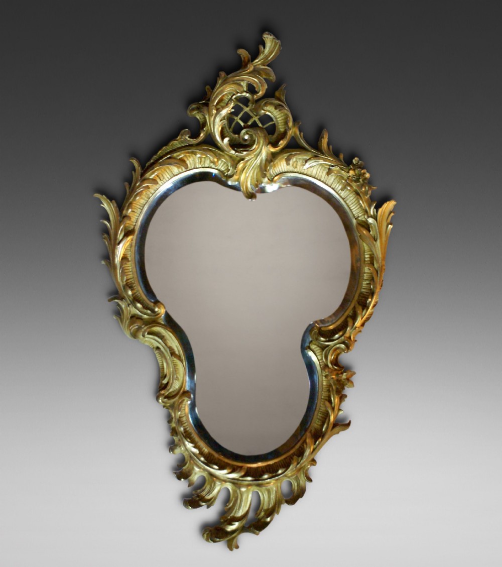 A 19th-century Rococo Revival wall mirror with an ornate gold leaf frame featuring carved acanthus leaves and lattice cresting.