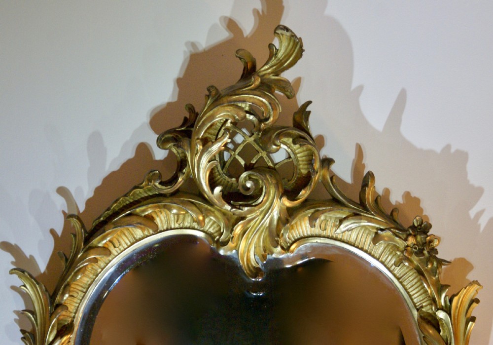 A 19th-century Rococo Revival wall mirror with an ornate gold leaf frame featuring carved acanthus leaves and lattice cresting. View II