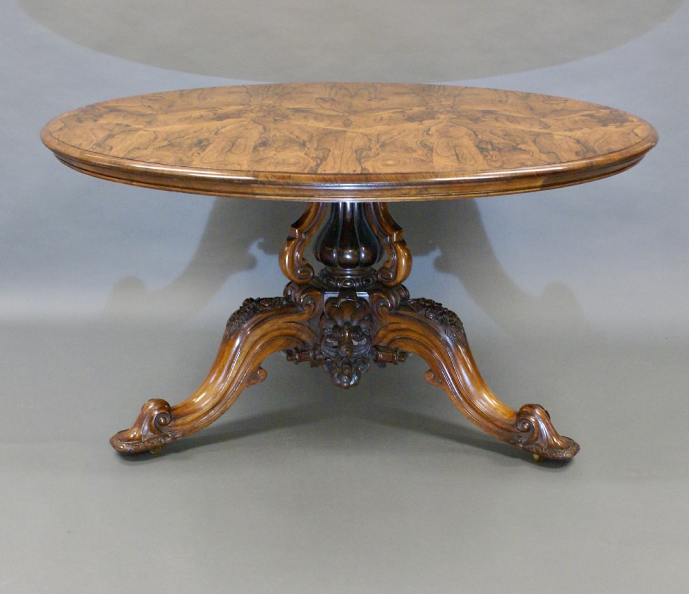 A circular rosewood centre table with a figured bookmatched veneered top shown tilted upright on a carved triform base. View V