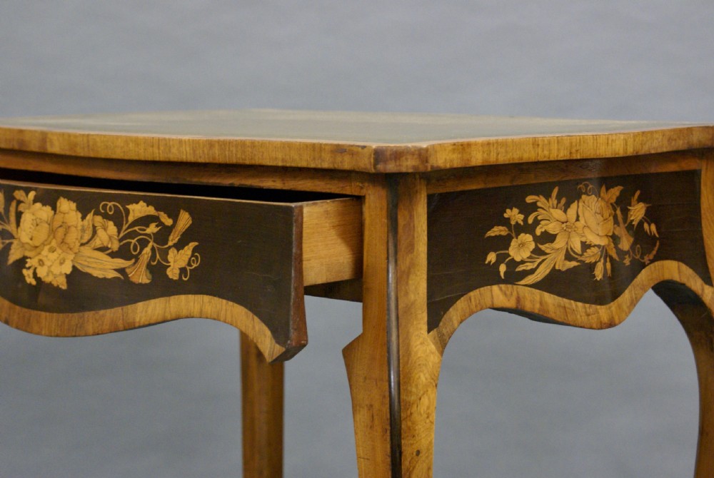 A French Rococo style writing table featuring curved cabriole legs, floral marquetry inlay on the dark apron, and a green leather inset top surface. View VII