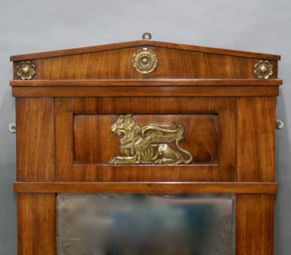 An Empire period mahogany wall mirror featuring a pedimented crest, classical ormolu rosettes, and a central gilded winged lion mount. View II