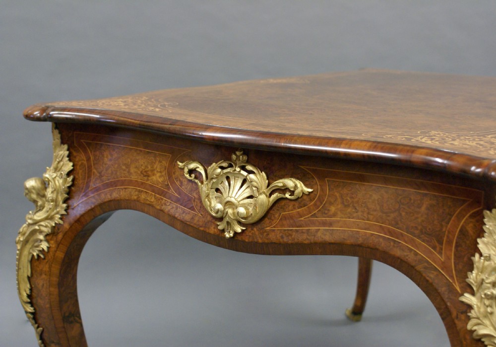 An English burr walnut bureau plat featuring gilt bronze ormolu mounts, a serpentine top, frieze drawers, and cabriole legs. View V