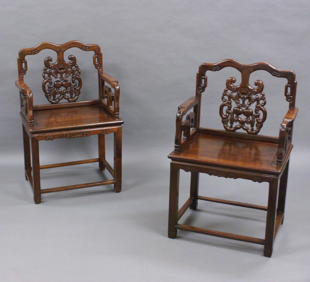 A pair of antique Chinese Qing dynasty dark hongmu armchairs featuring intricately carved openwork back splats and square mortise-and-tenon construction. View III