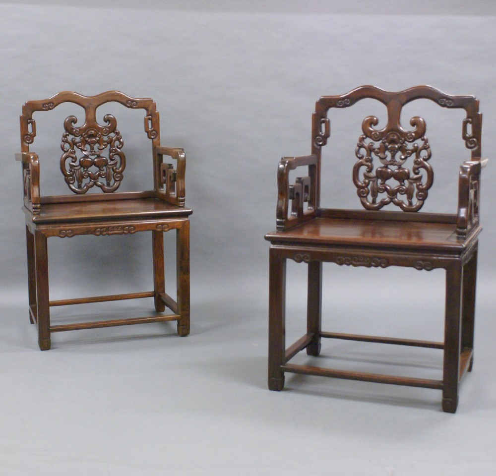 A pair of antique Chinese Qing dynasty dark hongmu armchairs featuring intricately carved openwork back splats and square mortise-and-tenon construction. View V