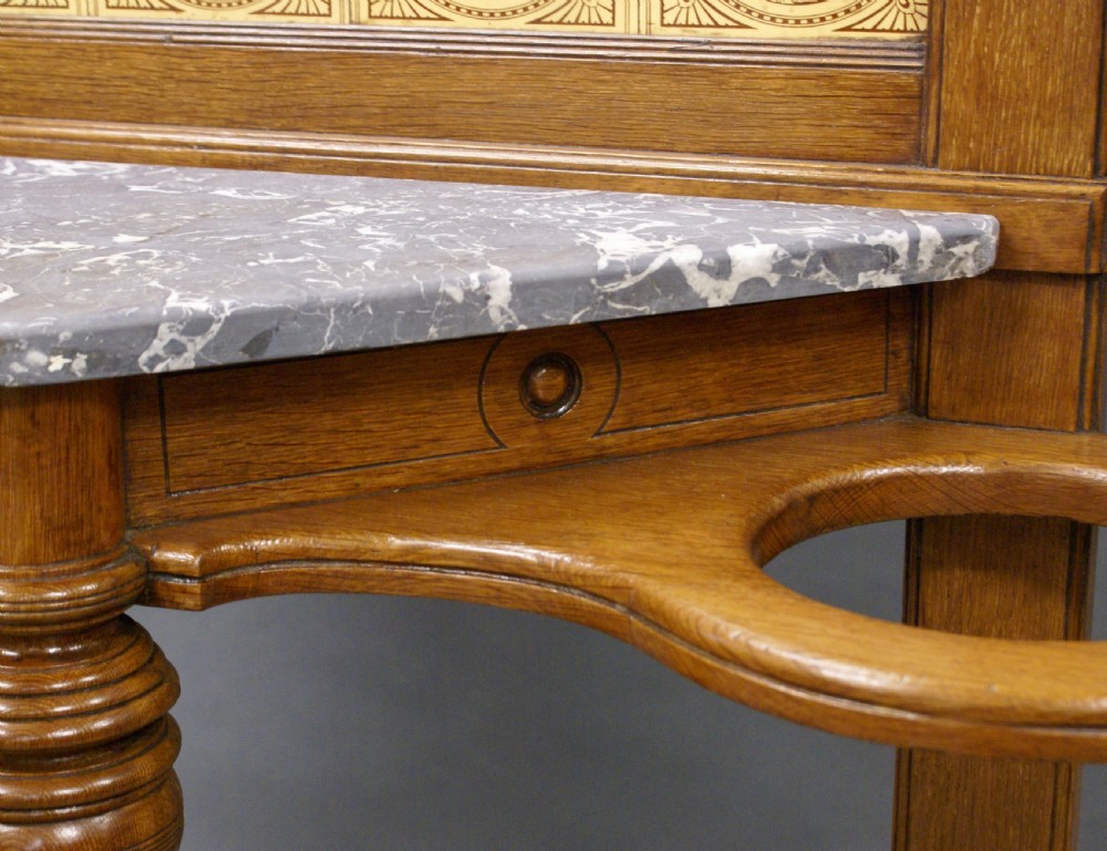 A Victorian oak hall stand featuring a central mirror, brass hooks, decorative tiles, a small marble shelf, and twin umbrella hoops above base drip trays. View III