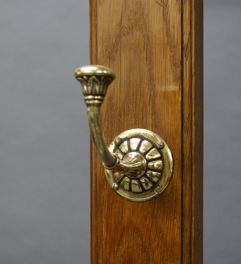 A Victorian oak hall stand featuring a central mirror, brass hooks, decorative tiles, a small marble shelf, and twin umbrella hoops above base drip trays. View VII