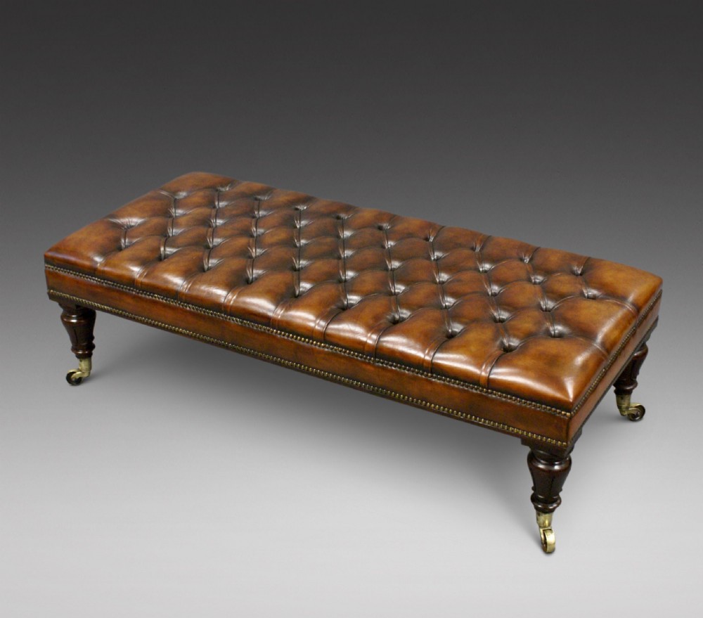 A large rosewood and leather upholstered stool.