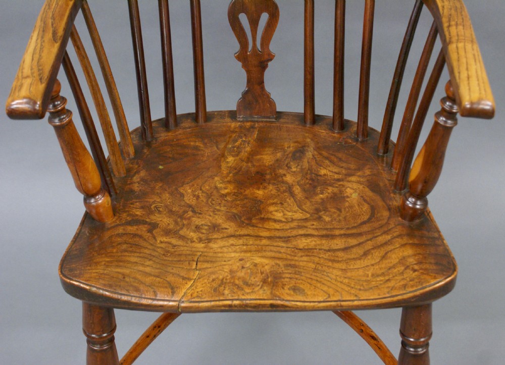 A warm brown antique Windsor armchair crafted from yew and elm, featuring a hoop back, pierced central splat, turned legs, and a curved stretcher. View III