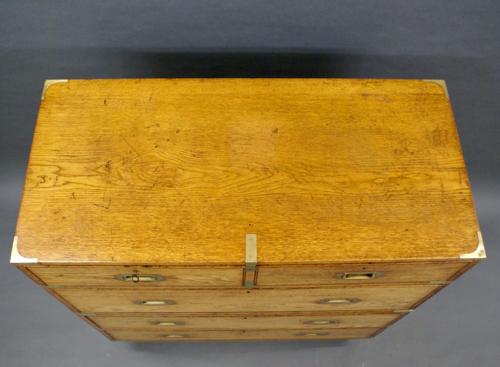 A two-part oak military campaign chest featuring two short over three long drawers, flush brass handles, protective brass corners, and turned feet. View V